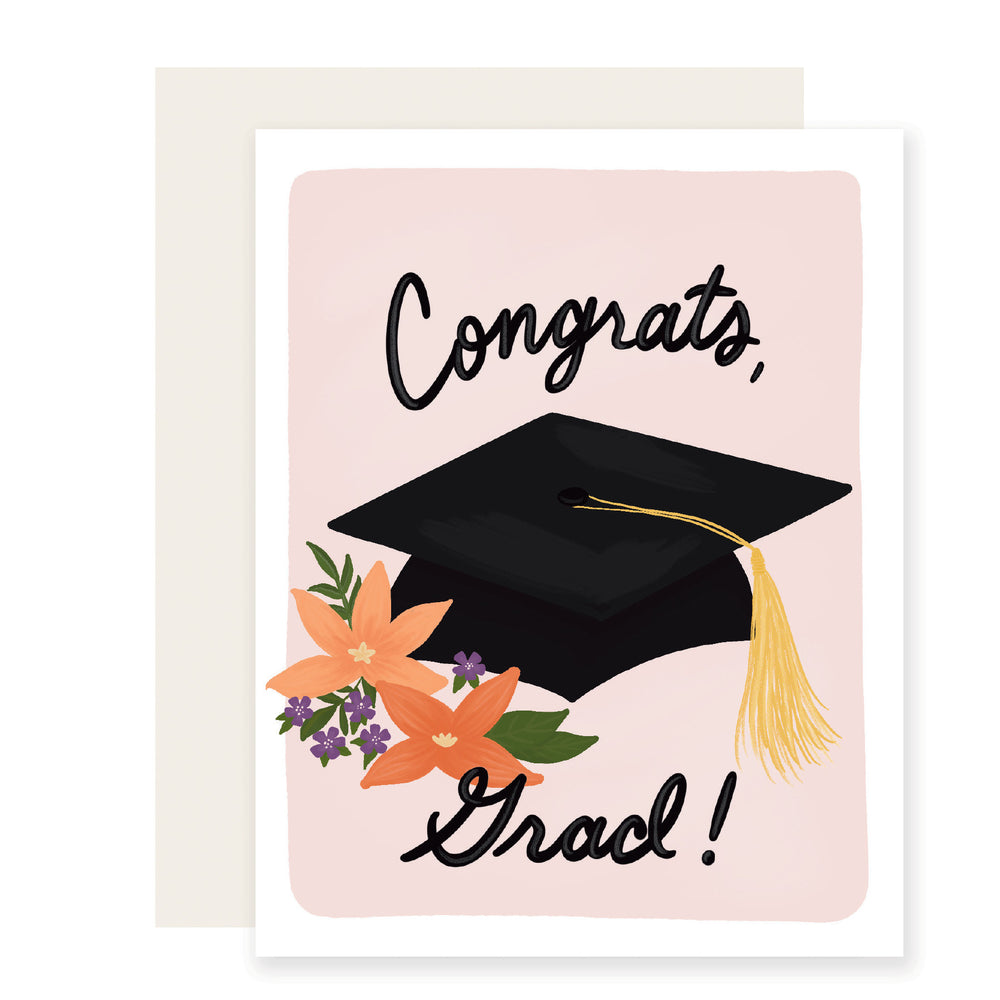 A light pink graduation card featuring beautifully illustrated flowers and a graduation cap with the text 'Congrats, grad!'. 