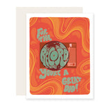 A Father's Day card featuring a vibrant illustration of a groovy record player. The card reads 'For the record, you're a great dad,' adding a playful pun. With an orange background and groovy yellow waves, it's perfect for the music-loving dad.