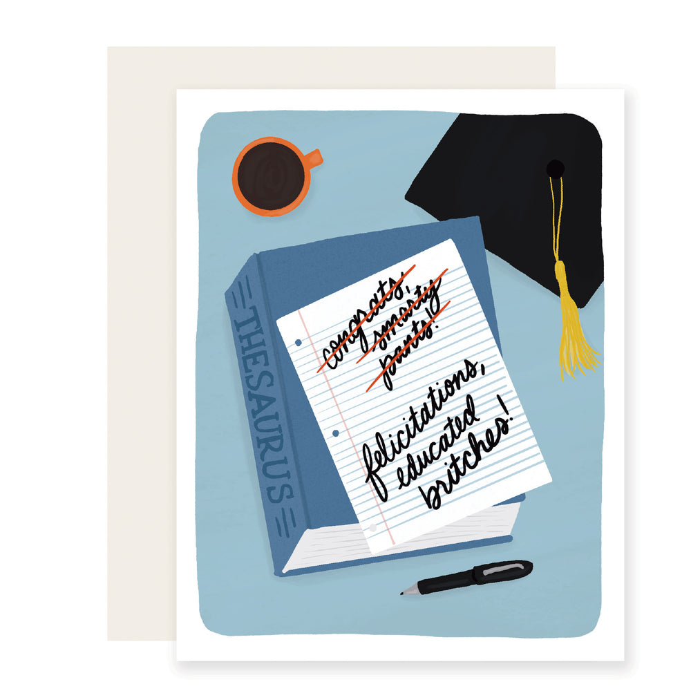 A graduation card with vibrant illustrations of a thesaurus with a piece of paper that reads 'Felicitations, educated britches.' Alongside, there's a delightful graduation cap and a cup of coffee, exuding warmth and celebration.