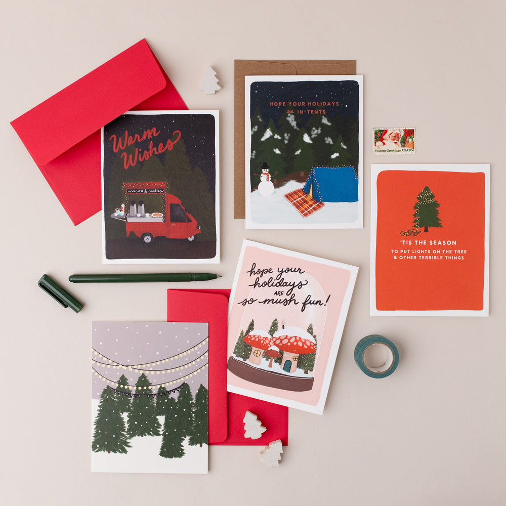 An assortment of beautifully illustrated Christmas cards, offering a range of sentiments from simple and elegant holiday wishes to witty and punny greetings, catering to a variety of tastes and holiday moods.