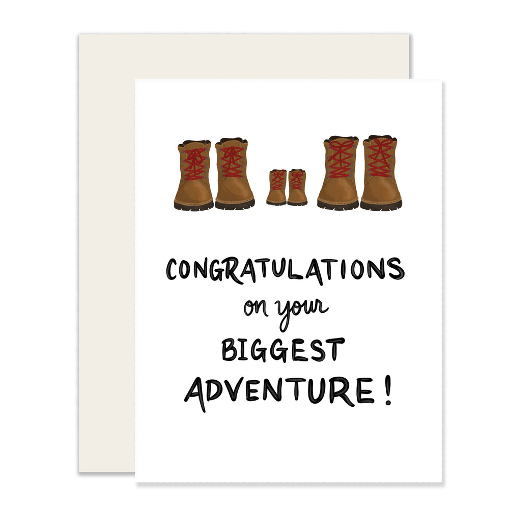 A simple baby card with the message 'Congratulations on your biggest adventure!' featuring three pairs of adorably illustrated hiking boots: two for the parents and a tiny pair in between, symbolizing the journey of parenthood.