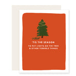 A funny Christmas card with an illustrated Christmas tree with half neatly strung lights and the other half humorously tangled. The card reads, 'Tis the season for tree lighting and other mishaps,' playfully poking fun at holiday decorating.