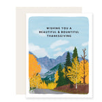 A beautifully illustrated Thanksgiving card with a vibrant autumn mountain scene, filled with warm-colored trees. The card reads, 'Wishing you a beautiful and bountiful Thanksgiving,' capturing the cozy spirit of the season.
