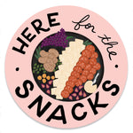 An illustrated sticker featuring a charcuterie board with various meats, cheeses, and snacks, accompanied by the text I'm here for the snacks. It conveys a lighthearted and delicious sentiment.