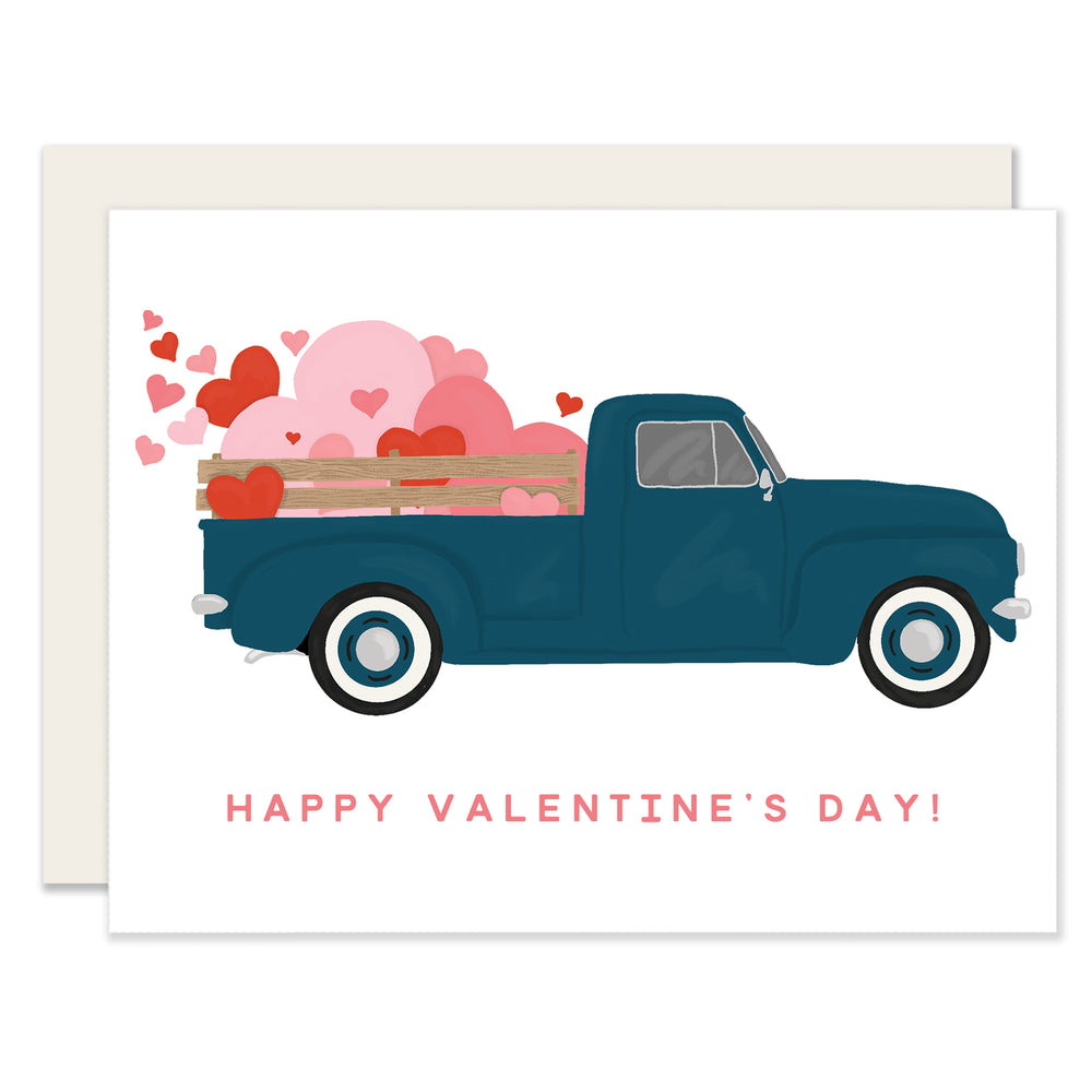 A Valentine's Day card with a cute vintage truck on the front, overflowing with red and pink hearts in its bed. The card displays "Happy Valentine's Day" in a festive font, combining a classic feel with holiday cheer.